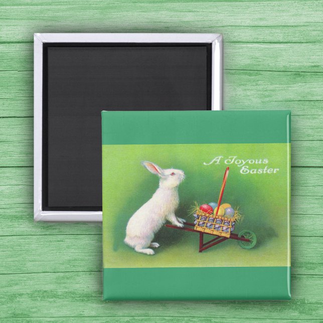 Joyous Påskhare and Wheelbarrow Magnet (White Easter Rabbit pushing wheelbarrow with coloured Easter Eggs on green Magnet.)