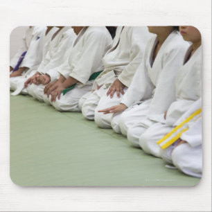 Judo-spelaren sitter ner till en rad musmatta