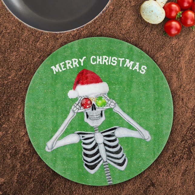 Jul Skeleton Shiny Ornaments Grönt Guld (Smiling Christmas skeleton shiny ornaments Santa hat on green with gold specks glass cutting board.)