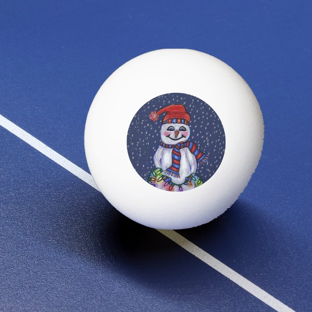 Julbelysning Leende Snöman Snöflingor Pingisboll (Smiling snowman in hat scarf holding bright string Christmas lights falling snow on ping pong ball.)