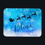 Jultomten och hans flygren - tro magnet<br><div class="desc">Julmagnet - böjlig stil,  med en svart silhouette av den santa ridningen i hans sleigh som dras av hans renflyg över himmlen. Tro skriftligt i en trendig skrivar stilsorten. Bakgrunden är design för snowflake för isigblått en frostig.</div>