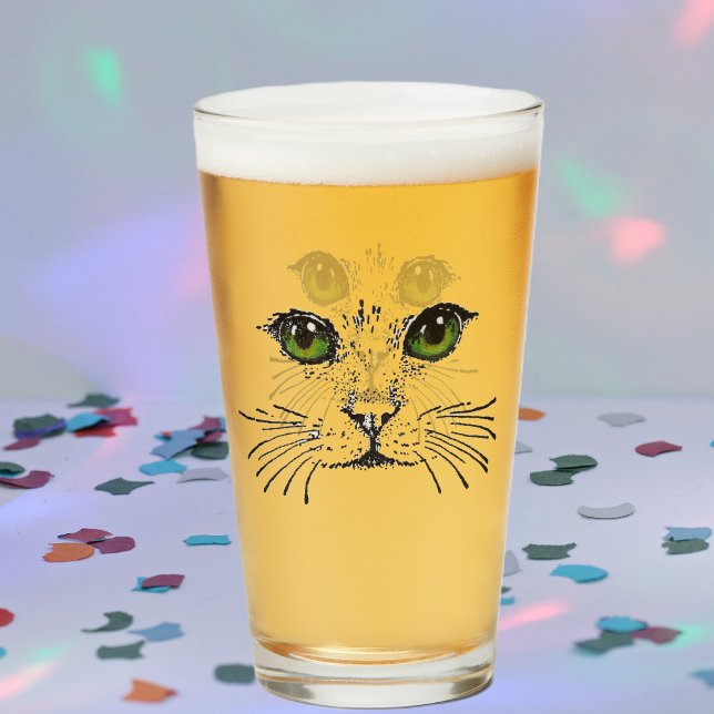 Kattansiktsillustration i svart med levande gröna  glaskopp (Drawing of black cat face with intense green eyes and whiskers on drinking glass.)