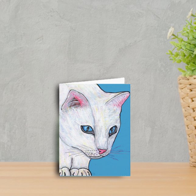 Katten för blåttögavit noterar kortet kort (White cat with vibrant blue eyes on blue notecard.)