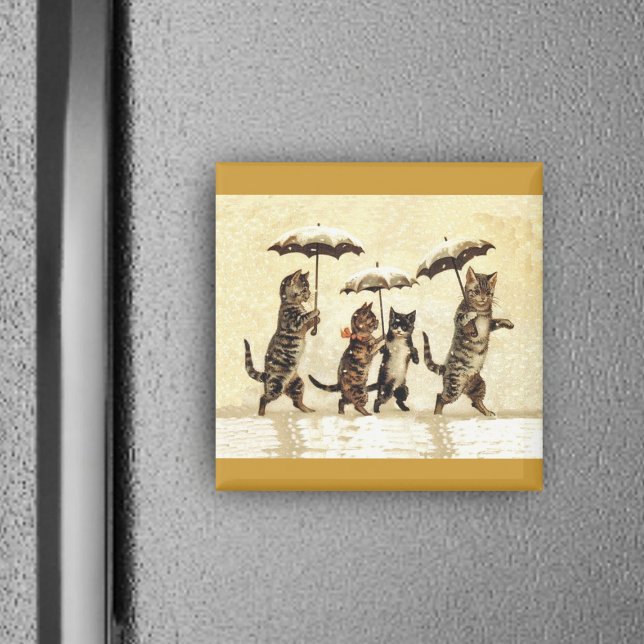Kattfamilj med paraplyer i Snö Magnet (Four brown cats walking upright in snow with umbrellas on yellow square magnet.)