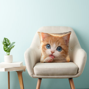 Kattunge med blå ögon slickar på tass kudde