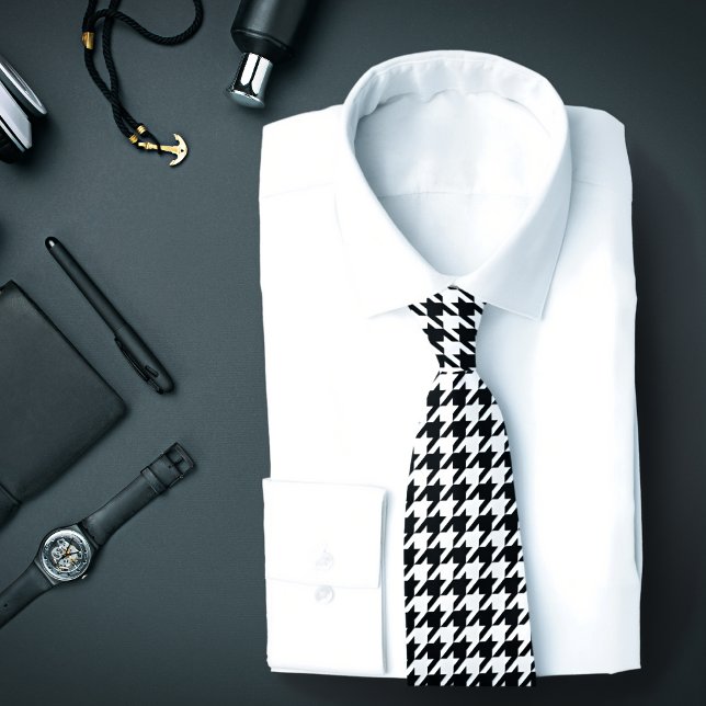 Klassisk svart-vit houndstooth-randig slips (A necktie with a B&W houndstooth pattern is featured on an assemblage of men's fashion accessories.)