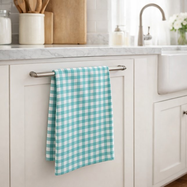 Klassiskt teal och vit gingham-mönster gårdshus kökshandduk (A kitchen towel featuring a gingham plaid pattern done in teal and white.)