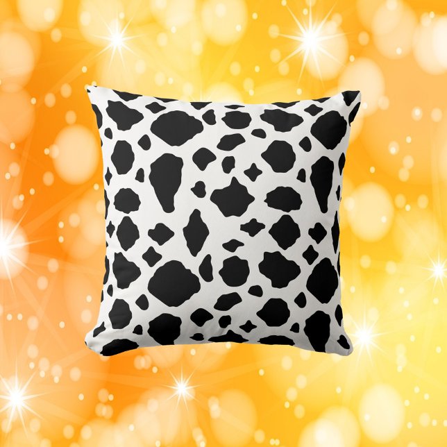 Ko-print-mönster svart och vitt kudde (A throw pillow with a black and white cow pattern)