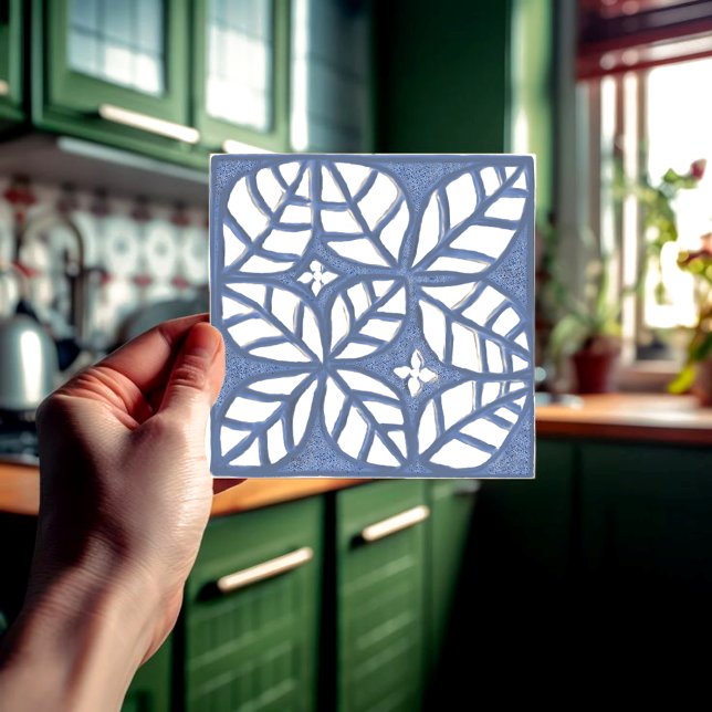 Köksbrickor, blått och vitt keramiskt T Kakelplatta (Blue and white ovate leaf ceramic tile held in a hand  in front of a green kitchen.)