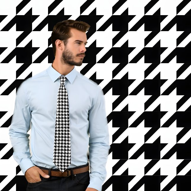 Kontrollruta för klassisk svart och vit houndstoot slips (Man wearing black and white houndstooth pattern necktie. He stands against wall with same pattern.)