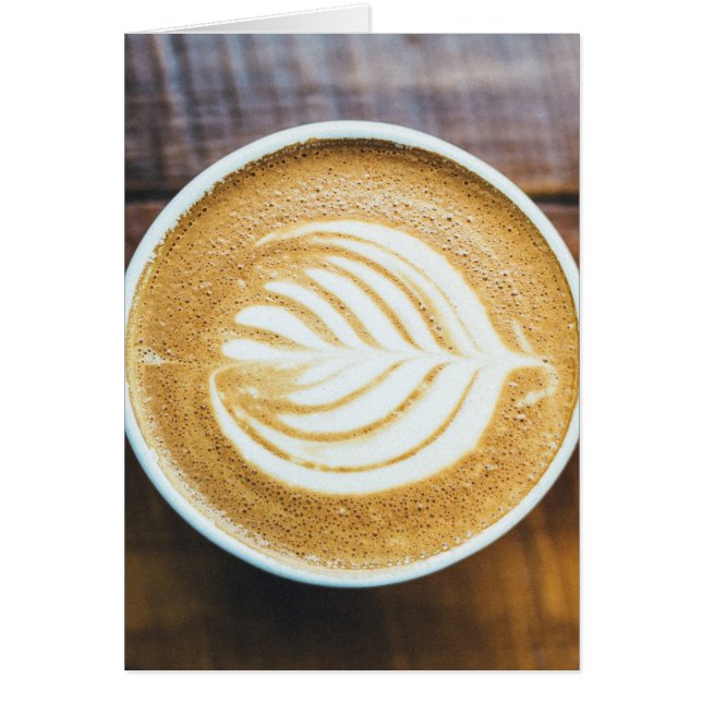 Kopp kaffelatte med bladformad skum på trä hälsningskort (Framsidan)