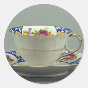 Kopp och såser med färgade blomdesigner på det. runt klistermärke