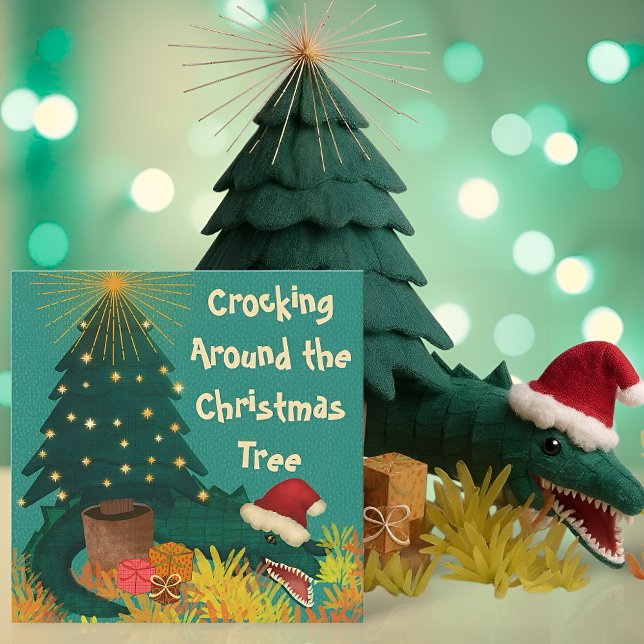 Korsning runt jul (Funny Christmas card with a crocodile in a Santa hat under a tree and the pun Crocking Around)