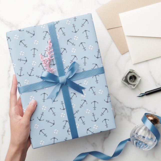 Kustnära små nautiska ankare kastade på mjukt blåt presentpapper (Gifting)