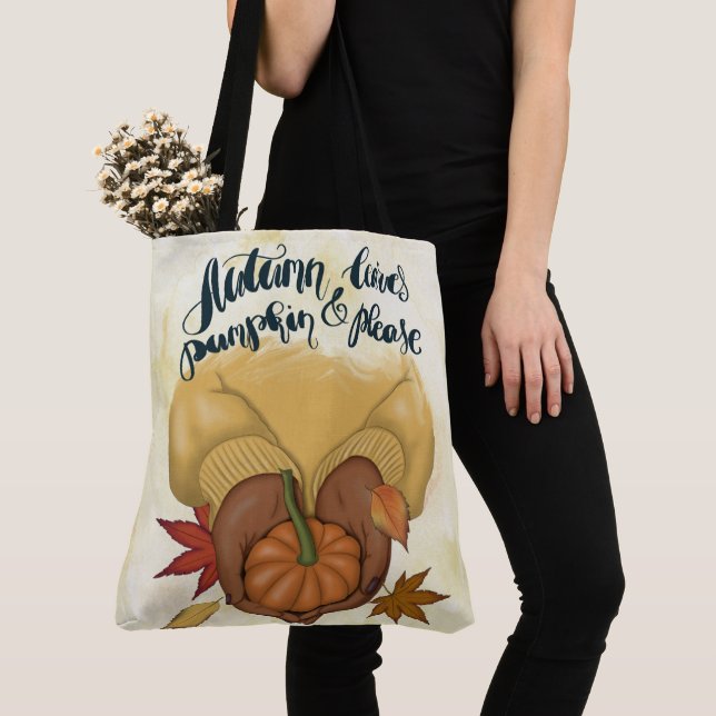 KVINNA I GULD SWEATER HOLDING TINY PUMPKIN TYGKASSE (Närbild)