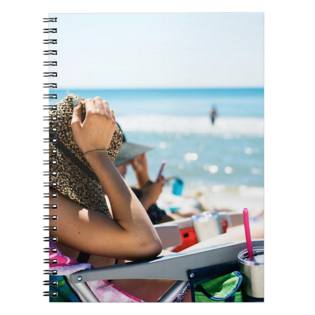 Kvinnor som ljuger på sol lounger som täcker henne anteckningsbok (Framsidan)