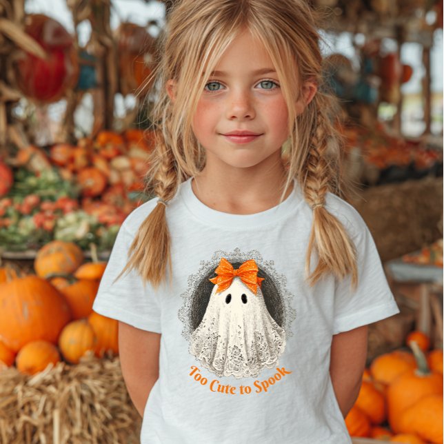 Lace Ghost in Orange Bow Ornate Frame Design T Shirt (Girl wearing a white shirt with a cute ghost illustration and "Too Cute to Spook.)
