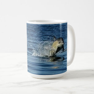 Lekfulla vanliga delfiner som hoppar genom havet kaffemugg