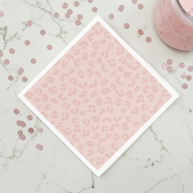 Leopardmönster i rosa pappersservett (A pink leopard print napkin on a white marble countertop with muted pink confetti and a pink drink.)