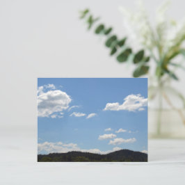 Liggande med grönt backe, träd och moln vykort