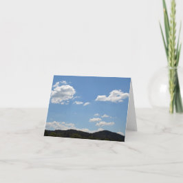 Liggande med grönt backe, träd och molnposte kort