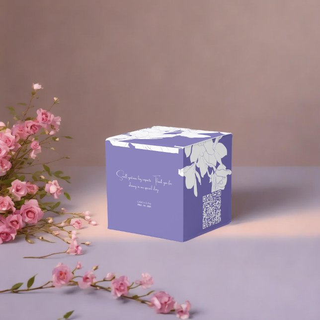 Lila av lyxblommor presentaskar (a purple floral favor box with a white flowers placed on soft surface surrounded with pnik flowers)