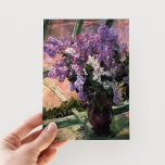 Lilacs i ett fönster | Mary Cassatt Vykort<br><div class="desc">Lilacs in a Window (1880) av Mary Cassatt är en delikat likhetskonstruktion som visar en vas fylld med vibrerande laktor placerad nära ett fönster. Konsten fångar skönheten hos friska blommor och den milda ljusfiltreringen genom glaset, vilket ger en känsla av lugn. Kassatts noggranna uppmärksamhet på detaljerna och hennes mjuka, Impressionistiska...</div>