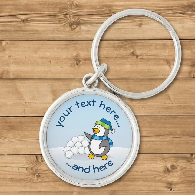 Lilla penguin med snö bollar som viftar rund silverfärgad nyckelring (Skapare uppladdad)