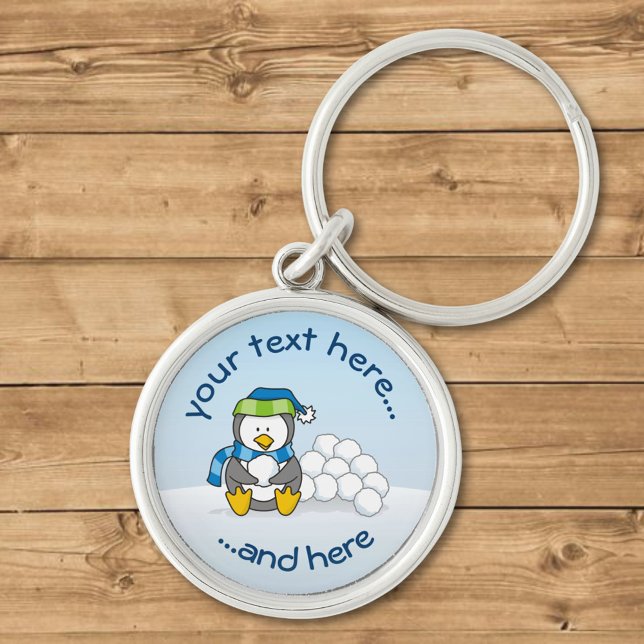 Lilla penguin sitta med snöbullar rund silverfärgad nyckelring (Skapare uppladdad)