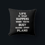 Livet är.. Funny Motivational Quote Kudde<br><div class="desc">"Livet är vad som händer när du är upptagen med att Skapar andra planer",  ett lustigt motiveringscitat. En kraftfull påminnelse om att vi kan skapa alla möjliga mål och ambitioner inför framtiden,  men när vi har en stark inriktning mot framtiden kan vi glömma att leva fullt ut under tiden.</div>