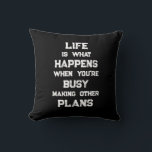 Livet är.. Funny Motivational Quote Kudde<br><div class="desc">"Livet är vad som händer när du är upptagen med att Skapar andra planer",  ett lustigt motiveringscitat. En kraftfull påminnelse om att vi kan skapa alla möjliga mål och ambitioner inför framtiden,  men när vi har en stark inriktning mot framtiden kan vi glömma att leva fullt ut under tiden.</div>