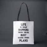 Livet är.. Funny Motivational Quote Tygkasse<br><div class="desc">"Livet är vad som händer när du är upptagen med att Skapar andra planer",  ett lustigt motiveringscitat. En kraftfull påminnelse om att vi kan skapa alla möjliga mål och ambitioner inför framtiden,  men när vi har en stark inriktning mot framtiden kan vi glömma att leva fullt ut under tiden.</div>