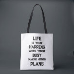 Livet är.. Funny Motivational Quote Tygkasse<br><div class="desc">"Livet är vad som händer när du är upptagen med att Skapar andra planer",  ett lustigt motiveringscitat. En kraftfull påminnelse om att vi kan skapa alla möjliga mål och ambitioner inför framtiden,  men när vi har en stark inriktning mot framtiden kan vi glömma att leva fullt ut under tiden.</div>