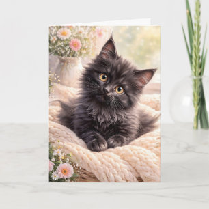 Ljus svart kattunge på stickad filt med blommor kort
