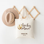 Lucky i Kärlek Horseshoe Wedding Favor Tygkasse<br><div class="desc">Konstruktionen har två guldhästskor och "Lucky in Kärlek" i varm höstens bruna vattenfärg. Underbar bröllopsförmån eller välkomstpåse för gäster från byn. Koordinerande tillbehör som finns i vår butik!</div>