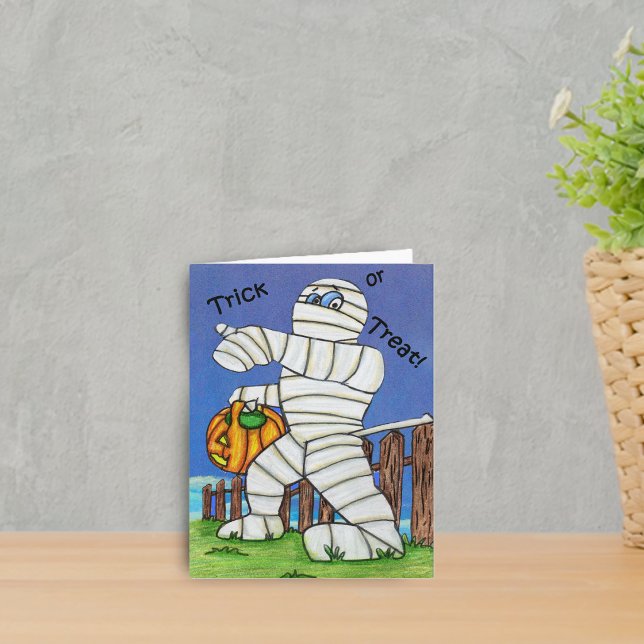 Mammabus eller godisHalloween kort (Cute Trick or Treat mummy by fence with pumpkin in grass on Halloween notecard.)