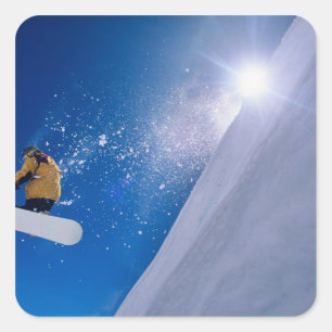 Man flyger genom luften på en snowboard med fyrkantigt klistermärke