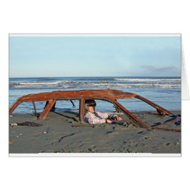 Man sitta i rostig bil på stranden hälsningskort