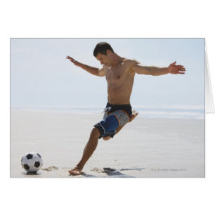 Man sparkar fotboll på stranden hälsningskort