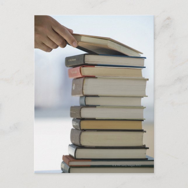 Man's hand taking a book from a stack of books vykort (Framsida)