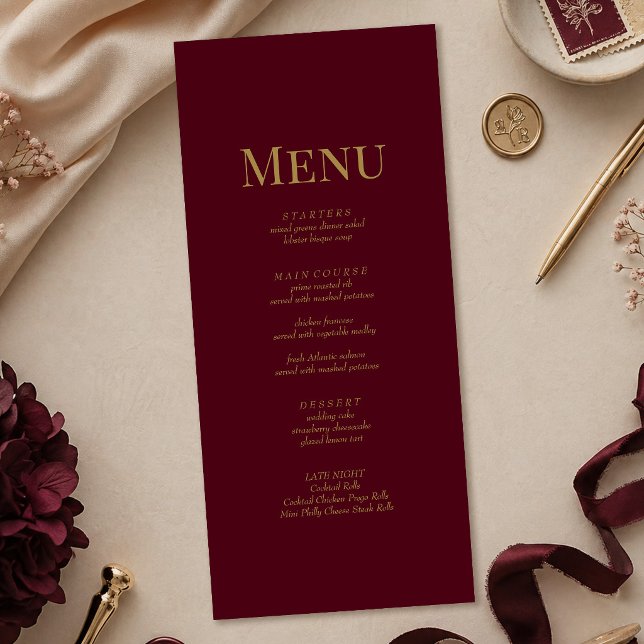 Minimalistisk Burgunder Guld Monogram Bröllopsmeny Meny (Minimalist Burgundy Gold Monogram Wedding Menu on a table with gold and burgundy wedding decor)