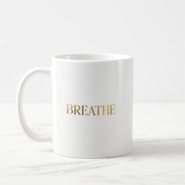 Minimalistisk typografi med guldet ordet andas kaffemugg (Vänster)