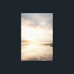 Misty Lake Sunrise Golden Reflection Canvastryck<br><div class="desc">Soft golden sunlight pierces through thick morning mist over a calm lake, creating a luminous path of reflection across the water. Tall reeds line the shore while distant trees fade into the haze, and the sky blends warm peach and rose tones into pale blue-gray. The composition radiates profound stillness, gentle...</div>