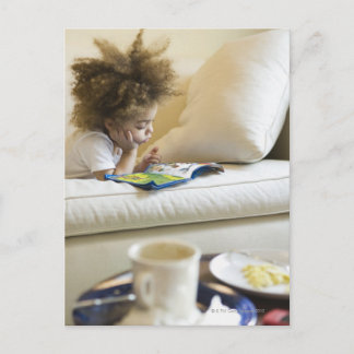 Mixed race boy reading book on sofa vykort