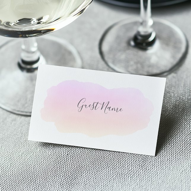 Mjukt vattenfärgsgäst namn-platskort för rosa placeringskort (Soft watercolor pink paint wash on a white guest name place card at a wedding dining table)