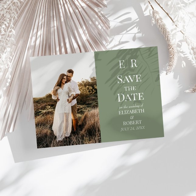 Modern Oliv Monogram Foto Spara Datum Kort (Modern Olive Monogram Photo Save the Date Card on a sunny white table with neutral dry botanicals.)