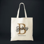 Modernt Monogram Namn  Svart Guld Script Brudtärna Tygkasse<br><div class="desc">Den moderna eleganta monogramväska i svart med guldfärgad text, totebag, kombinerar sofistikation med praktiskhet. Denna tote har ett snyggt svart tyg med elegant guldfärgad monogram-text, vilket gör den både stilren och personlig. Det rymliga innandömet är perfekt för dagliga tillbehör, medan de robusta handtagen säkerställer komfort och hållbarhet. Perfekt för shopping,...</div>