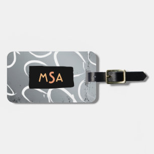 Monogram på svart på silverbotten med vita cirklar bagagebricka