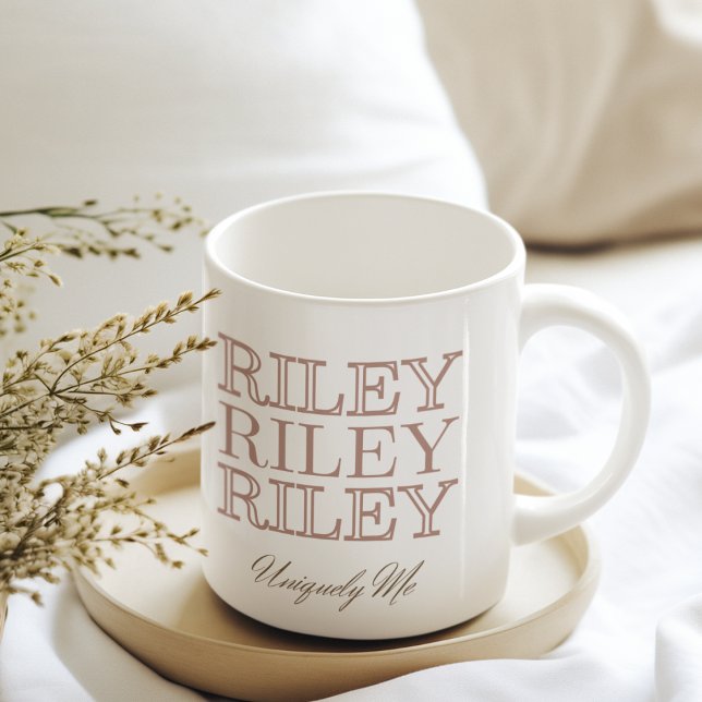 Monoline med kollisionsskydd kaffemugg (White mug featuring repeated all-caps name design with soft dusty clay text accents.)