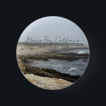 Morro Bay California Coastal Photography Knapp<br><div class="desc">A foggy overcast day in Morro Bay California with the ocean waves hitting the rocks on the shore in this beach photograph souvenir. This seaside travel photo keepsake button features black cursive script above the beach rocks and grey sky.</div>